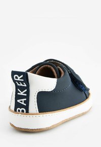 Chaussure en cuir marine avec accents blancs, doublure intérieure beige et dos texturé. Équipée d'une sangle Velcro et d'une semelle cousue.