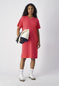 Vestido de algodón rojo con mangas cortas y corte recto, combinado con zapatillas blancas y un bolso bicolor. Diseño simple, textura suave.
