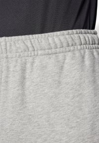 Graue Baumwollsweatpants mit einem elastischen Bund. Der Stoff hat eine weiche Textur und ein leichtes Melange-Muster, geeignet für legere Kleidung.
