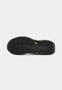 Black rubber shoe sole with deep tread patterns and green accents. Notable logo in the center; designed for traction and durability.