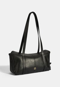 Zwarte leren handtas met lange platte handvatten, een strak ontwerp, opvallende stikdetails en een klein gouden logo-accent aan de voorkant.