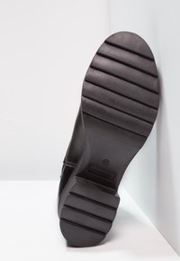 Suela de bota de cuero negro con textura acanalada. Punta redonda y suela de goma plana y flexible. Talla marcada 37.