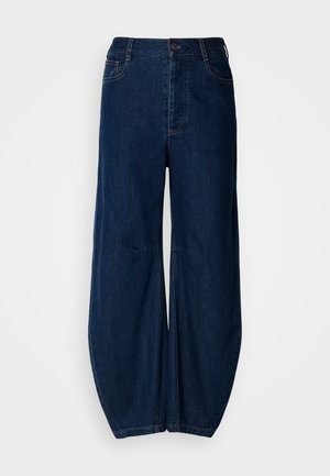 Jean large en denim bleu foncé avec une taille haute, une fermeture à bouton et deux poches avant. Présente une texture lisse et des coutures visibles.