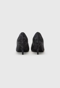 Black high-heeled shoes made of textured fabric, featuring scattered rhinestones and a pointed toe design, with slim stiletto heels.