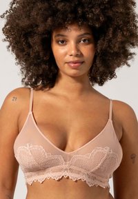 Vaaleanpunainen pitsinen bralette ohuilla säädettävillä olkaimilla, jossa on kukkakuosiset pitsiyksityiskohdat ja sileä satiinimainen materiaali.