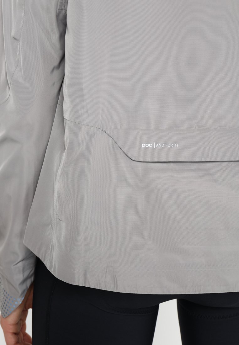 Helles graues Jacket aus Ripstop-Gewebe, mit abgerundetem Saum und "POC AND FORTH" Branding, einer glatten Textur und subtiler Schattierung.