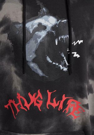 Sudadera negra con diseño de teñido anudado que presenta una gran gráfica gris de la cara de un lobo y texto estilizado en rojo que dice "THUG LIFE" en la parte inferior. Tejido suave, capucha ajustable.