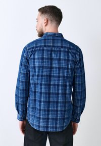 Blau kariertes Langarmhemd in verschiedenen Blautönen, mit Knöpfen an den Manschetten und einem abgerundeten Saum. Aus leichtem Stoff gefertigt.
