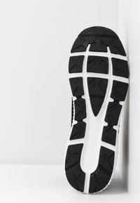 Sole di scarpa sportiva in bianco e nero con un motivo testurizzato, caratterizzata da scanalature profonde e vari elementi di trazione per un migliore grip.