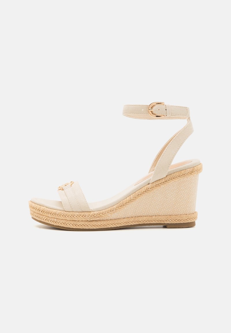 Sandale compensée beige avec bride à la cheville, bout ouvert et semelle plateforme à texture tissée, vue de profil sur fond blanc.