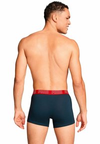 Boxer da uomo in tessuto blu scuro, con una vita elastica rossa con il marchio 'PUMA', che offre una vestibilità aderente e una texture liscia.