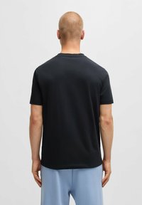 T-shirt noir à manches courtes avec un col rond, texture lisse et coupe standard, présenté de dos.