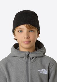 Black knit beanie atop a light grey zip-up fleece jacket. The jacket features a hood and a white logo on the left chest area.