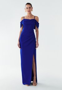 Obleka, ki se prilega telesu, dolžine do tal v kraljevsko modri barvi, z odkrito ramo, stranskim razporkom in teksturiranimi paneli na prsnem košu.