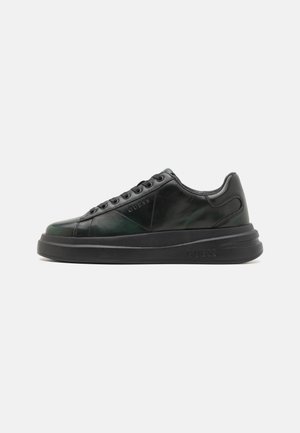 Sneaker in pelle nera con finitura lucida, dotate di un pannello testurizzato, lacci piatti e una suola nera spessa. Logo impresso di lato.