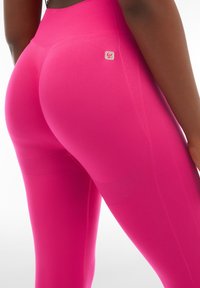 Leggings fucsia a vita alta realizzati in tessuto elastico, con una texture liscia e dettagli del logo discreti vicino all'elastico in vita.