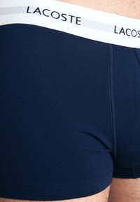 Marineblauwe katoenen boxershorts met een witte elastische tailleband met het "Lacoste"-logo. Gladde textuur met een aansluitend ontwerp.