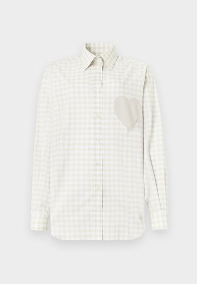 Πουκάμισο με μακριά μανίκια και κουμπιά, με μπεζ και λευκό καρό μοτίβο, που διαθέτει μια μεγάλη υφασμάτινη καρδιά στο αριστερό στήθος.