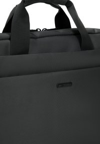 Schwarze, strukturierte Laptop-Tasche mit stabilen Obergriffen und Reißverschluss. Subtile Markierung auf der Vorderseite fügt ein raffiniertes Detail hinzu.
