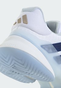 Hellblauer Sportschuh mit strukturiertem Obermaterial, weißer Zwischensohle und gemustertem Gummiaußensohle. Mit goldfarbenen Akzentdetails.