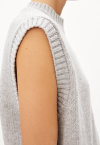 Jasnoszary sweter bez rękaw�ów z prążkowanym dekoltem i otworami na ramiona, charakteryzujący się miękką teksturą i czystym, minimalistycznym designem.