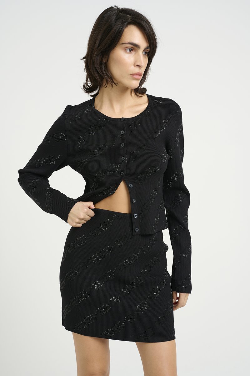 Black ribbed co-ord set featuring a cropped button-up cardigan and a fitted mini skirt, both with a subtle pattern and textured fabric.