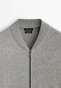 Szary dziany sweter z prążkowanym kołnierzem, pełnym suwakiem z przodu i subtelną fakturą. Metki widoczne na linii szyi dla identyfikacji marki.