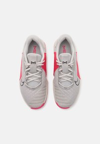 Zapatillas deportivas grises con acentos en rosa. Parte superior de malla, mediasuela texturizada y logotipo negro en contraste. Cintas redondas y cuello acolchado.