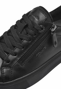 Baskets en cuir noir avec une fermeture éclair sur le côté, des lacets texturés et une semelle en caoutchouc robuste avec des détails de logo. Finition lisse dans l'ensemble.