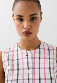 Abito senza maniche a quadri in bianco, rosa, nero e beige, con scollo rotondo e chiusura frontale con bottoni, realizzato in un tessuto leggero.
