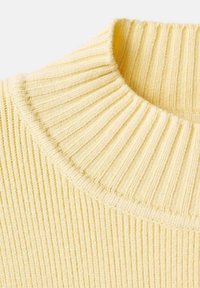 Jersey de punto acanalado con un alto cuello doblado en una suave tela amarilla. Presenta rayas verticales y un acabado texturizado.