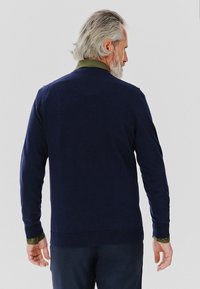 Granatowy sweter z zielonym kołnierzykiem, dzianinowa tekstura, długie rękawy, żebrowany dół, widziany z tyłu, o luźnym kroju.