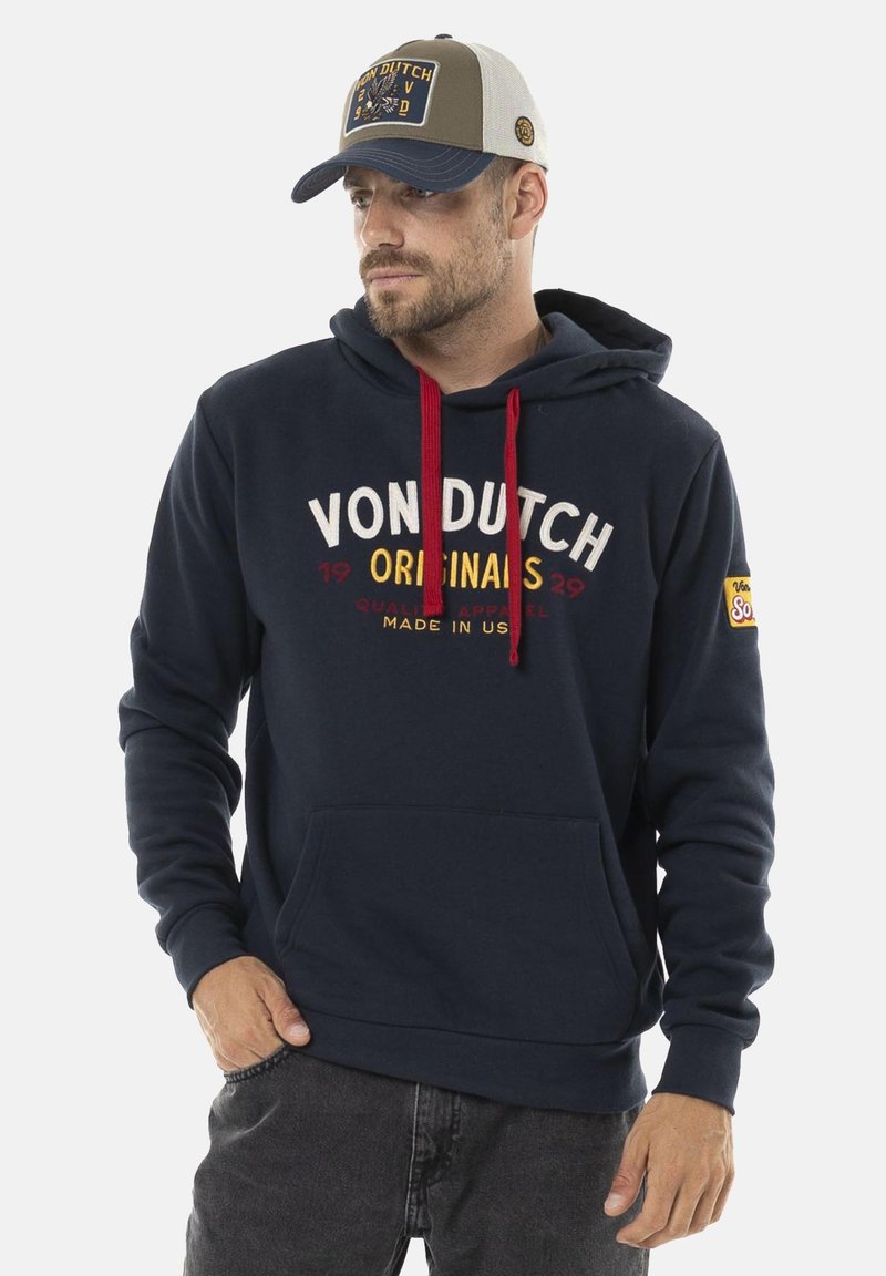Sweatshirt à capuche marine avec des cordons rouges, poche kangourou à l'avant et lettrage blanc. Assorti à une casquette grise et beige avec un logo.