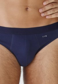 Mutande da uomo blu navy con una texture liscia, caratterizzate da un design minimale e un piccolo logo sull'elastico. Le cuciture sono visibili.