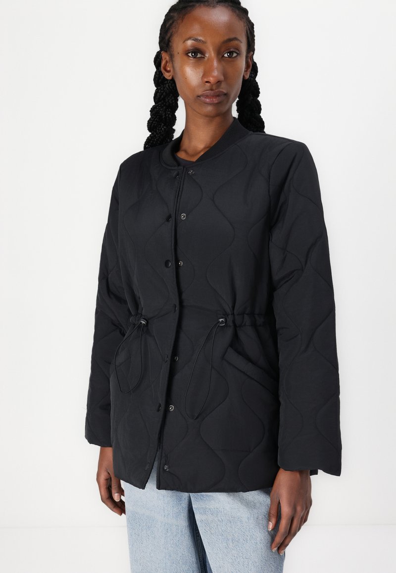 Schwarze gesteppte Jacke mit einem strukturierten Wellenmuster, Druckknopfverschluss vorne, verstellbaren Kordeln in der Taille und langen Ärmeln.