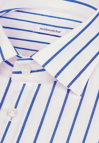 Chemise blanche à rayures verticales bleues, col boutonné, avec une étiquette « seidensticker » à l'intérieur du col.