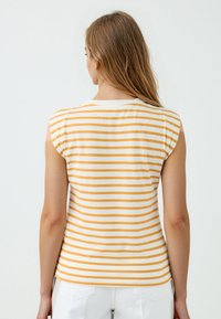 Gestreepte mouwloze top in een gele en witte katoenmix, met een ronde halslijn en een aansluitende snit, voorzien van zichtbare stikseldetails.