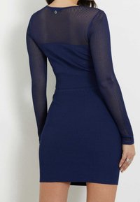 Navy Kleid mit einem enganliegenden gerippten Saum und langen Netzärmeln, ausgestattet mit einem Rundhalsausschnitt und einem kleinen Logodetail auf der Rückseite.