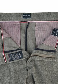 Grijze geruite broek met een marineblauwe voering, rode accenten en gestreepte binnenzakken. Voorzien van een rits en een verzorgingslabel.