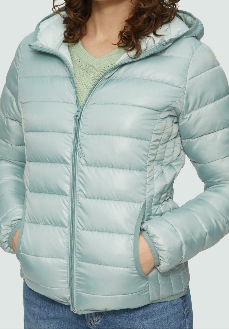 Chaqueta acolchada azul claro con capucha, con secciones acolchadas horizontales, cierre de cremallera y bolsillos laterales. Textura suave.