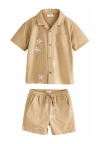 Camicetta a maniche corte con colletto e pantaloni abbinati in tessuto beige chiaro, con ricami bianchi di palme e una tasca sul petto anteriore.