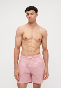 Κόκκινα και λευκά ριγέ μαγιό με ελαστική μέση και κορδόνι. Φτιαγμένα από ελαφρύ ύφασμα με χαλαρή εφαρμογή.