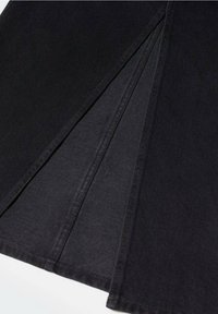 Falda de mezclilla negra con detalles plisados, que presenta una textura suave y costuras limpias. La tela tiene un ligero brillo, que realza el diseño general.