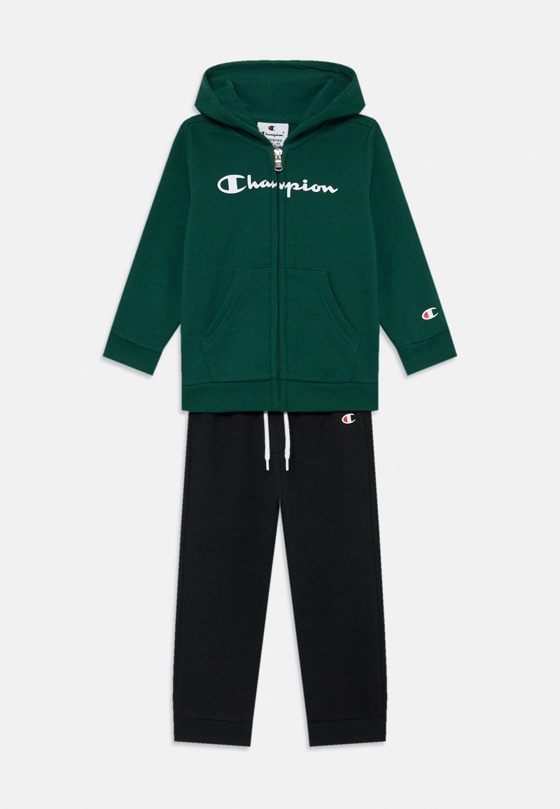Sweatshirt verde com o logo "Champion" branco, fecho em zip, bolsos frontais. Calças de fato pretas com cintura elástica e cordão branco, com punhos nas ankles.