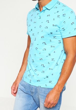 Polo bleu clair en coton, orné d'un motif de petits bateaux, d'oiseaux et de palmiers. Manches courtes et design de col classique.