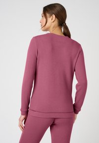 Maglietta a maniche lunghe in morbido tessuto testurizzato, con scollo rotondo e vestibilità rilassata. Colore: malva tenue. Dettaglio delle cuciture all'orlo.