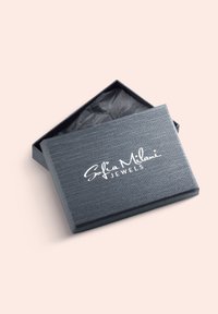 Grå smykkeboks med en tekstureret overflade, der har et hvidt logo "Sofia Milani JEWELS." Låget er åbent, hvilket afslører krøllet sort silkepapir indeni.