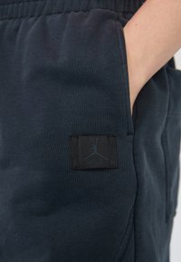 Mornarske trenerice od mekog materijala, s crnom Jordan oznakom na đepu i elastičnim pojasom za udobnost.