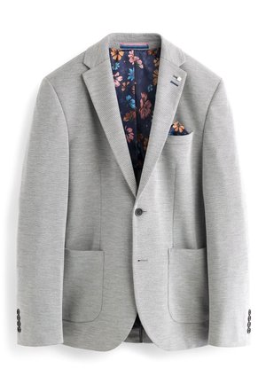 Grijze blazer met twee voorzakken, met gesneden revers en een enkele knoopsluiting. Gevoerd met een donkere stof met bloemmotieven.