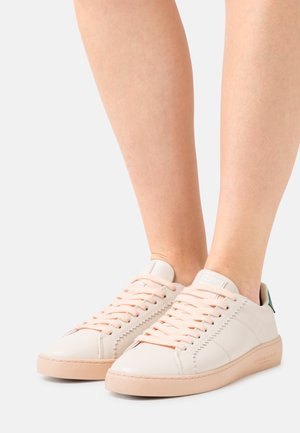 Vita lädersneakers med en persikofärgad gummisula och matchande skosnören. Har sydda detaljer och en liten grön logotyp på hälen.